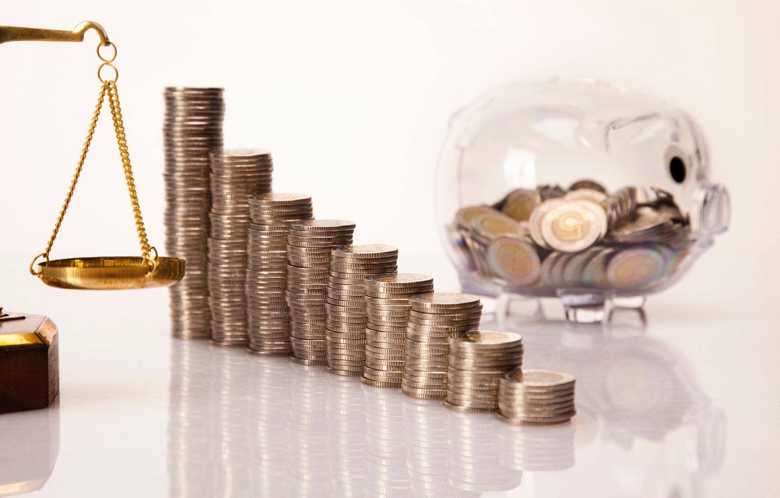 Economia - geral - dinheiro - finanças - orçamento - recursos públicos, - tributos - reforma tributária Uma pilha de moedas está em cima da mesa, ao fundo há um porquinho com moedas dentro