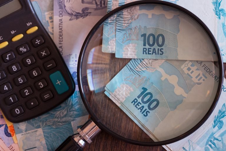 Notas de dinheiro, uma lupa e uma calculadora