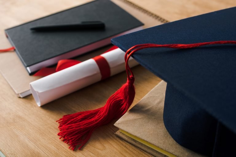 Chapéu de formatura em cima da mesa ao lado de um diploma