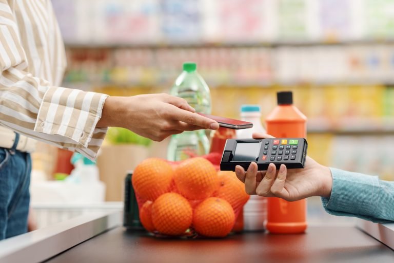 Uma mulher paga compras num mercado com o celular