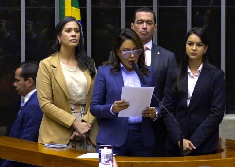 Deputados estão em pé ao lado do microfone