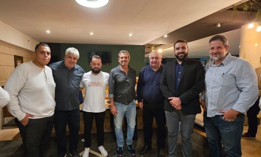 Sete homens de pé abraçados. O secretário Rodrigo Peleteiro ao centro. 