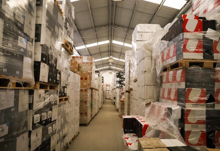 Galpão de armazenamento com muitas caixas empilhadas, embaladas para envio