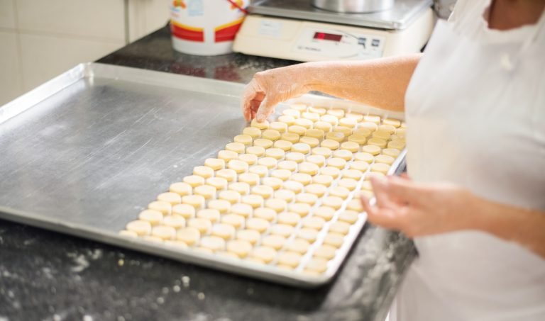Microempresa - mulher coloca biscoitos em tabuleiro para assar