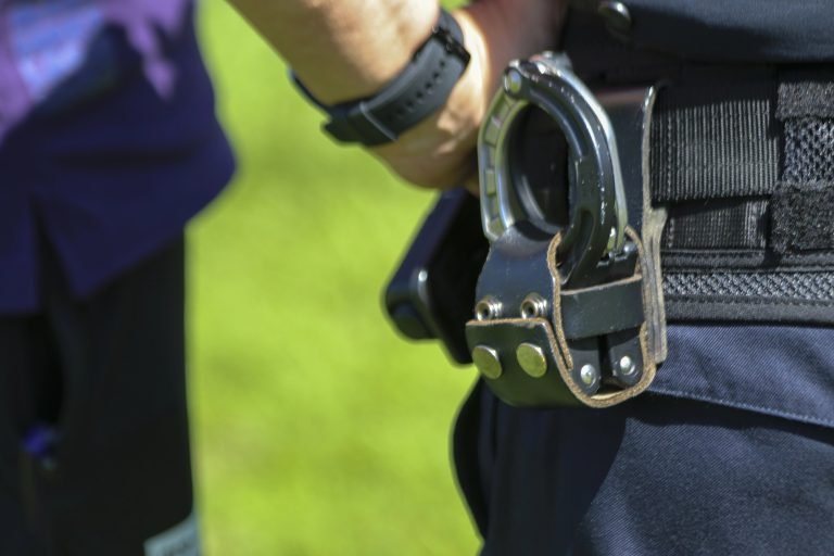 Policial com algema e arma na cintura